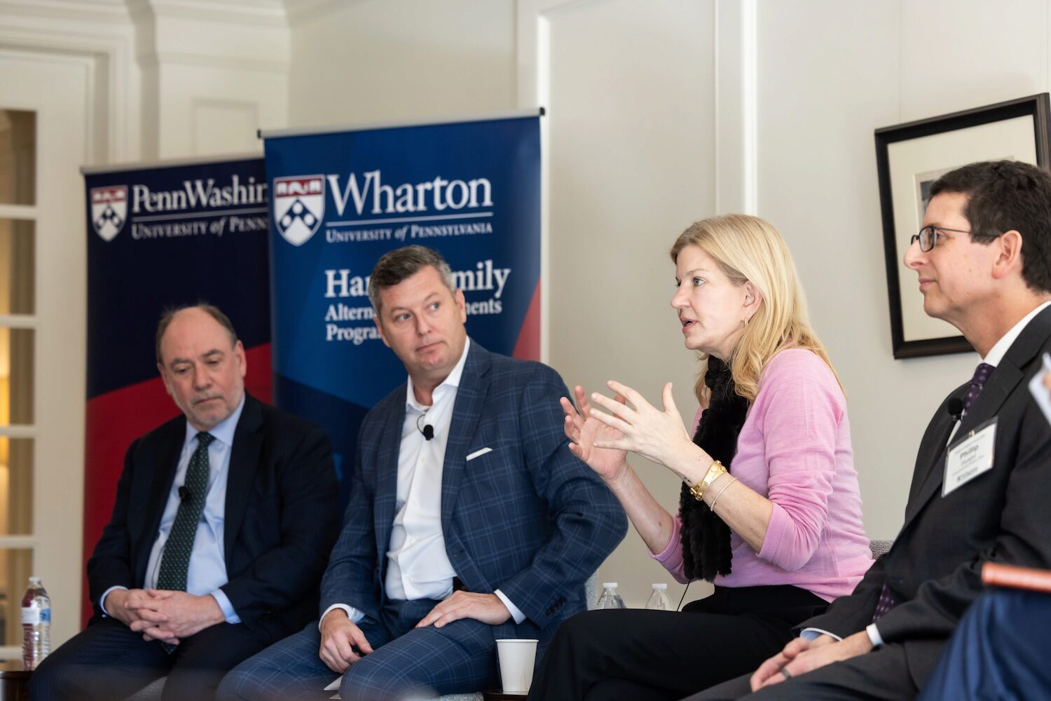 A panel speaker motions while speaking. Other speakers watch on