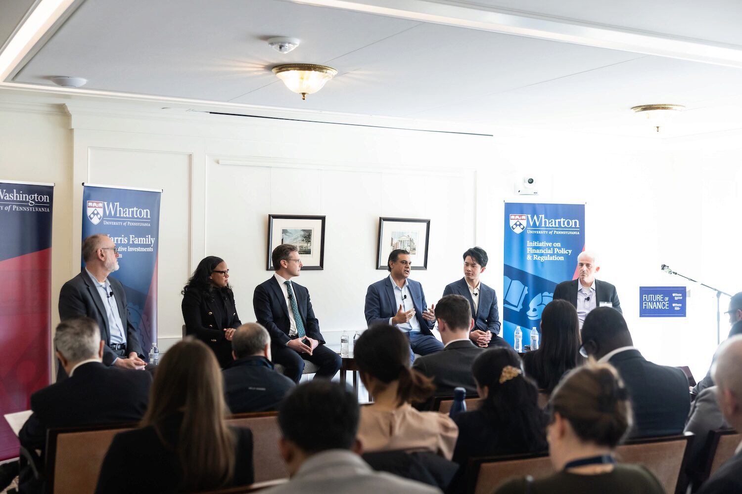 Six conference speakers before an audience