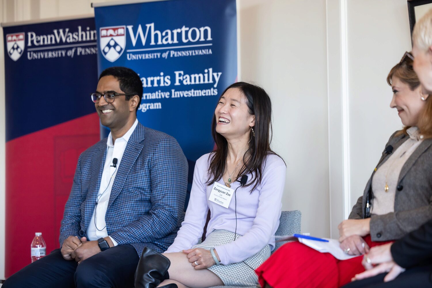 Panelists smiling and laughing while seated onstage at a conference