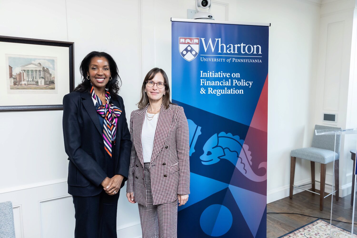 Two people post in front of a blue pop up banner for a group photo