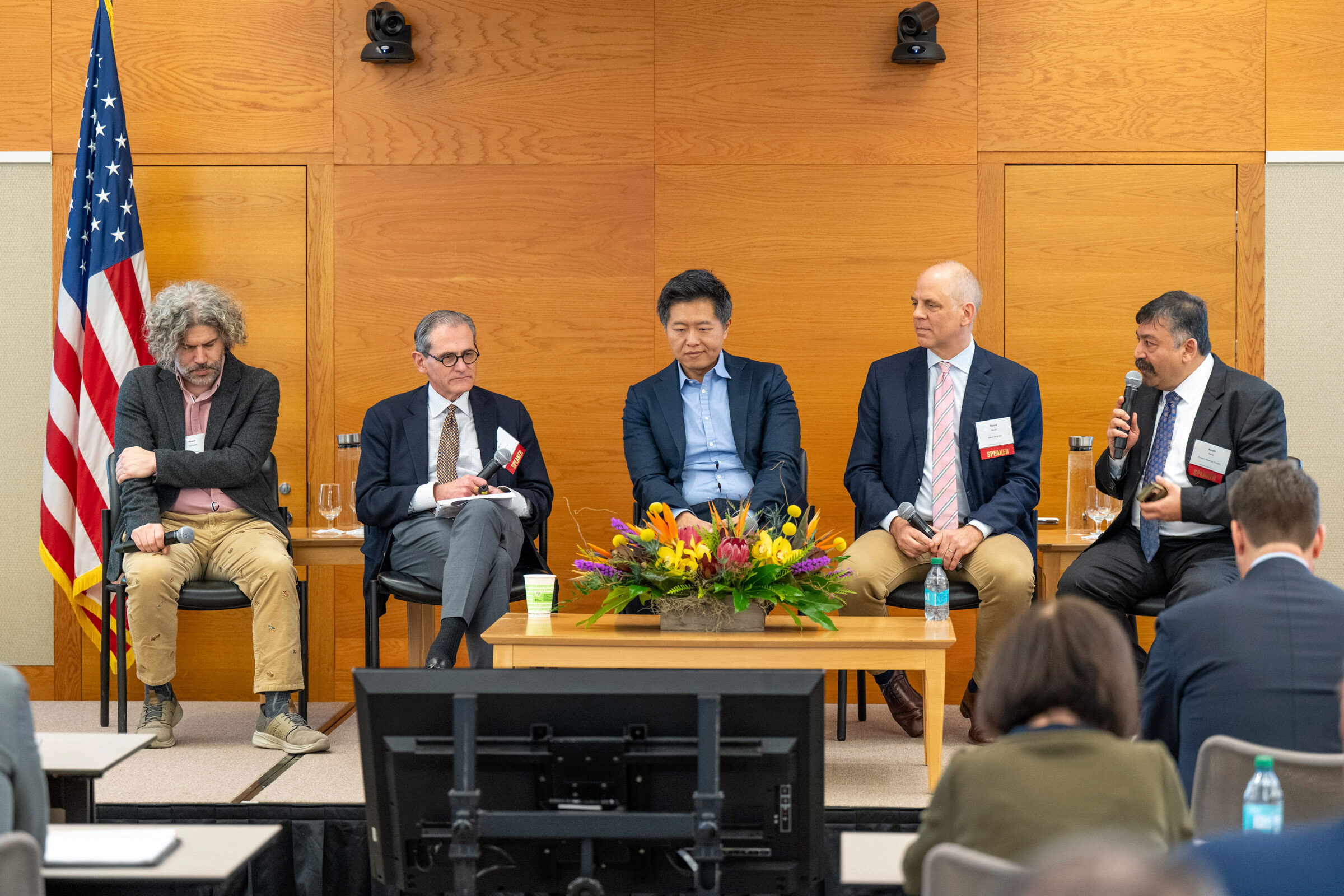 Five people sit on a panel behind a coffee table