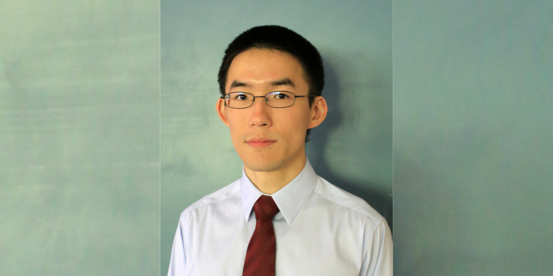 A person smiles toward the viewer before a light green background